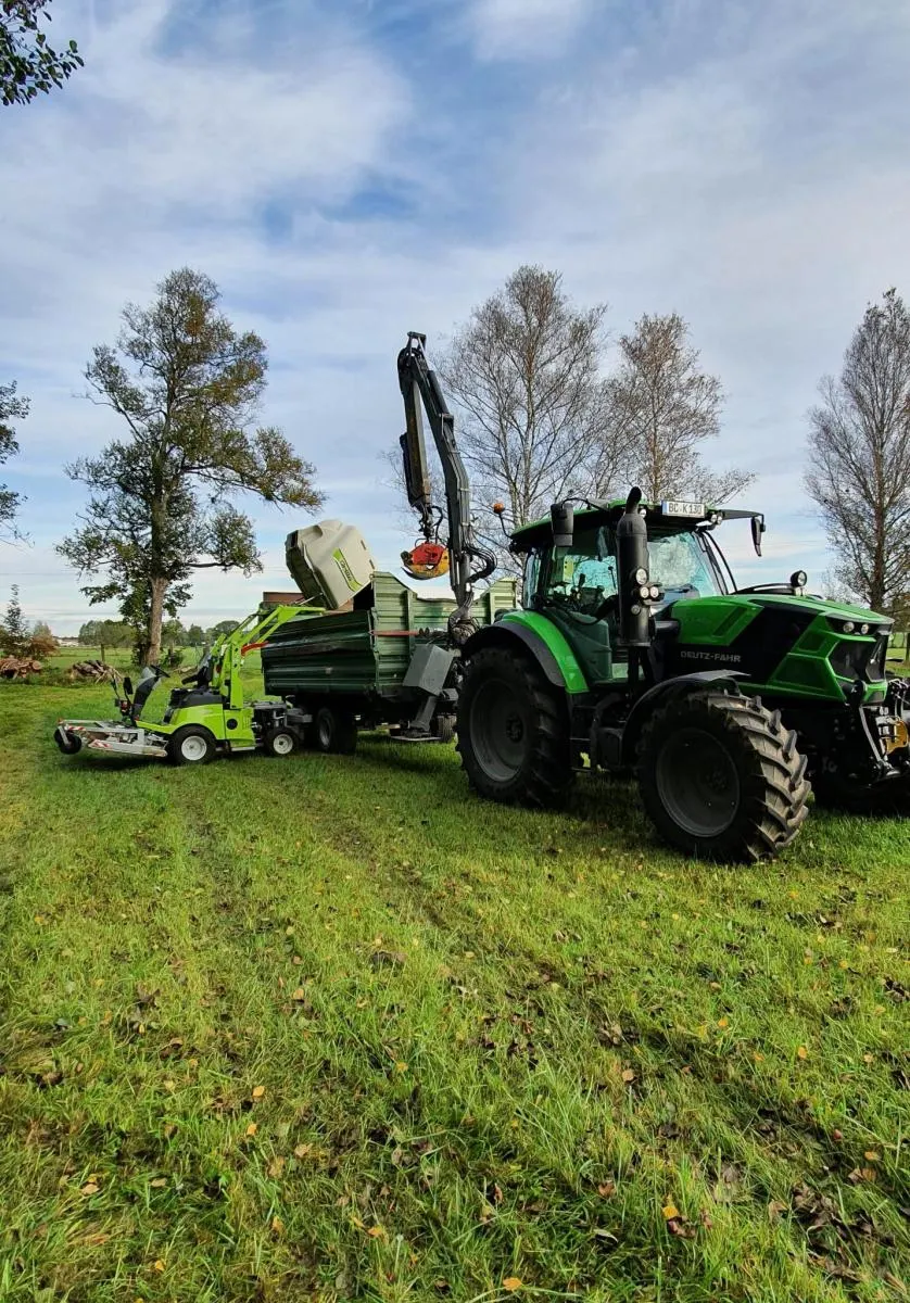 Traktor mit Anbaugerät auf einer Wiese